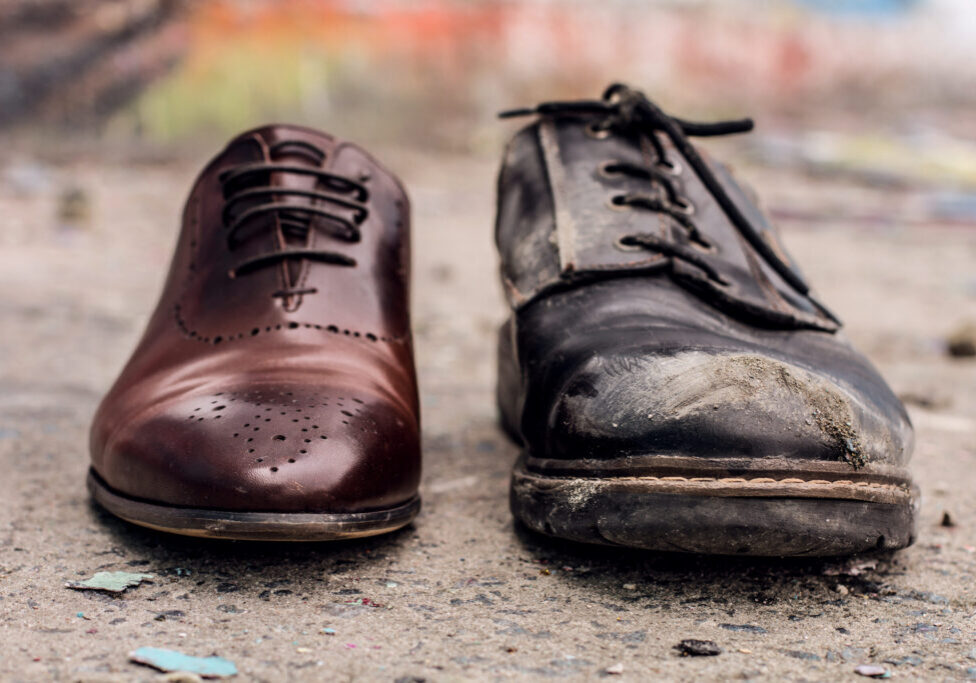 Conceptual shooting of shoes. Old shabby shoes in comparison with new and expensive ones.