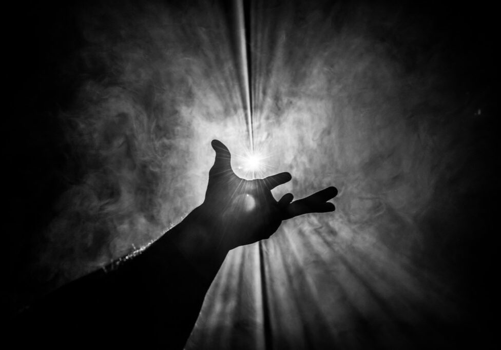 Hand reaches out to hold and touch the light